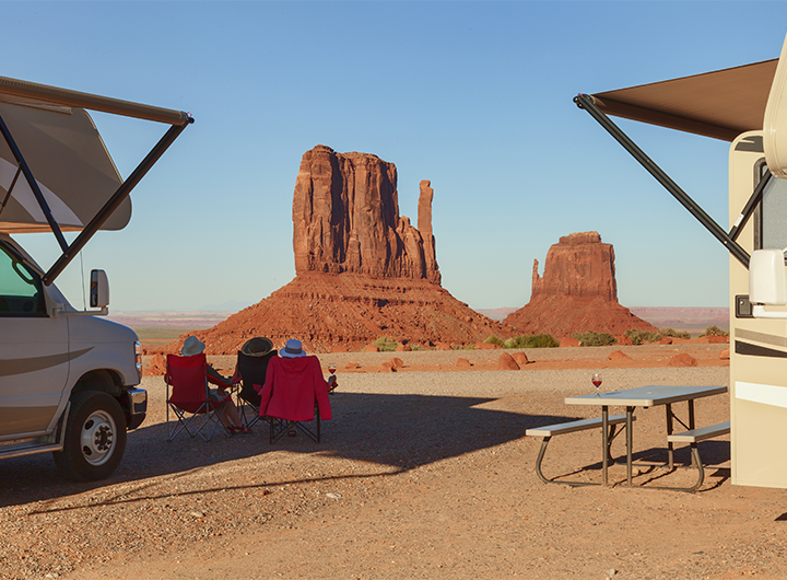 two rvs and people sitting in chairs in front of mountain 