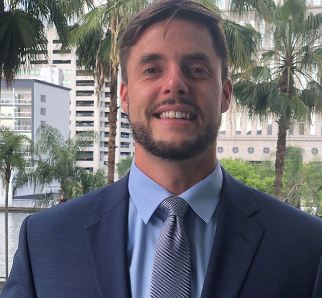 Greyson Glaves in a suit and tie stands outdoors.