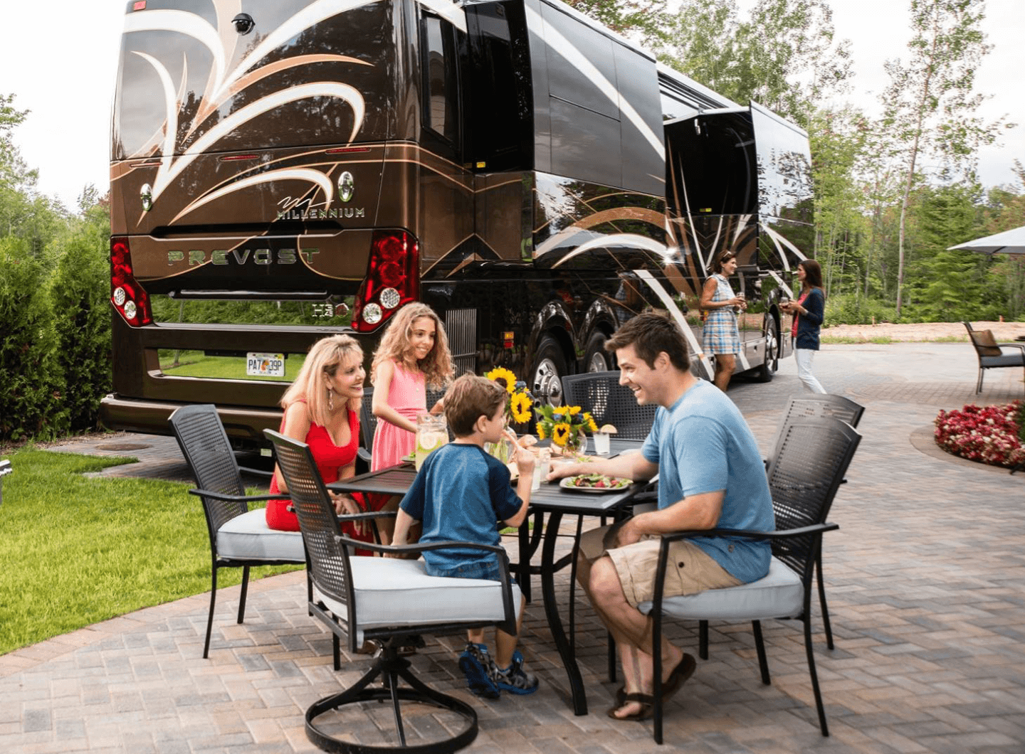Family eating at a table in front of luxury RV