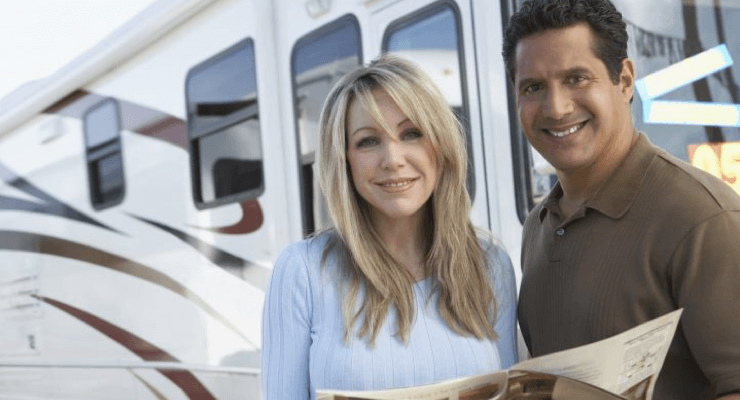 Couple standing in front of RV with magazine