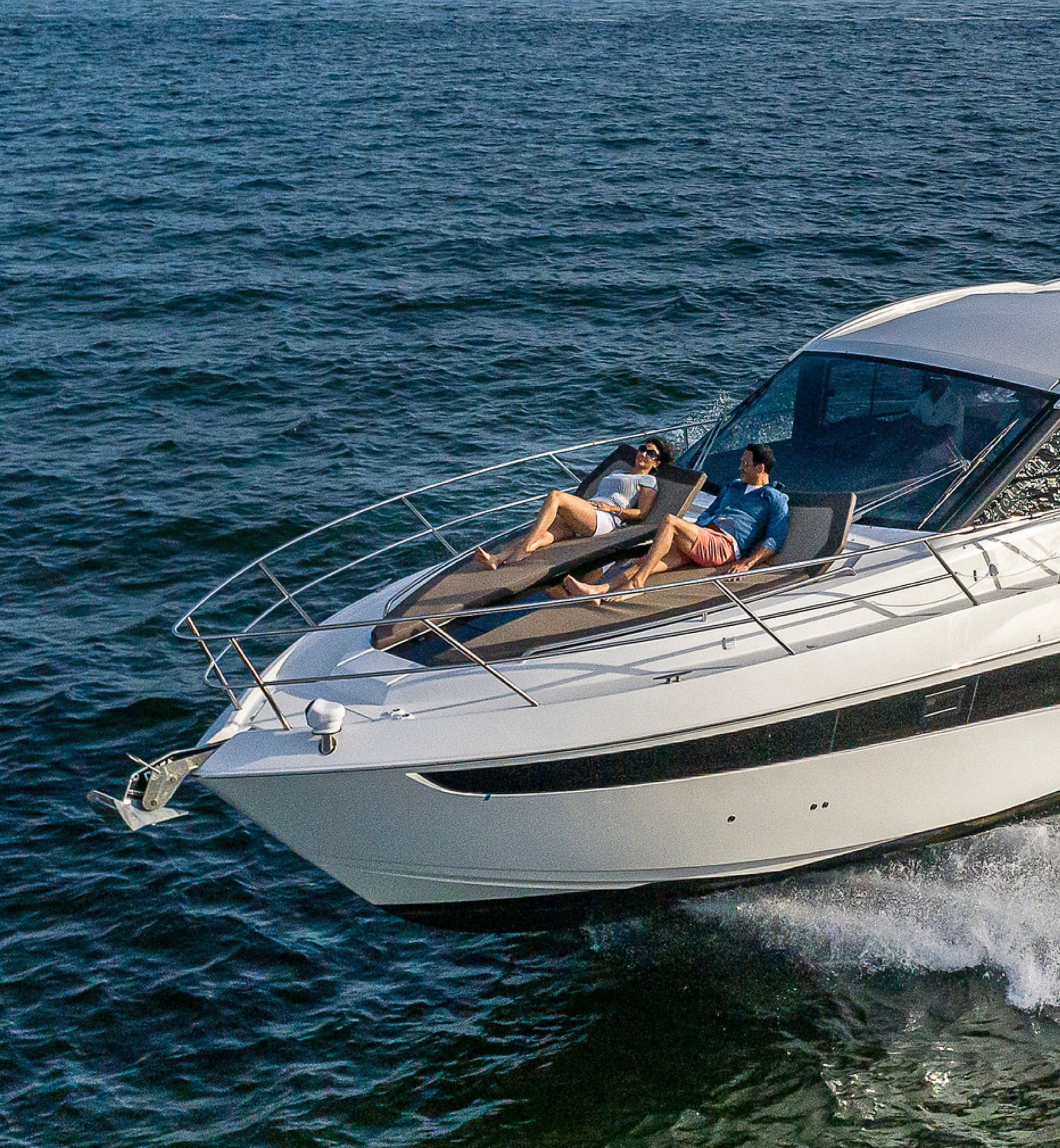 Couple lounging on bow of yacht as it sails