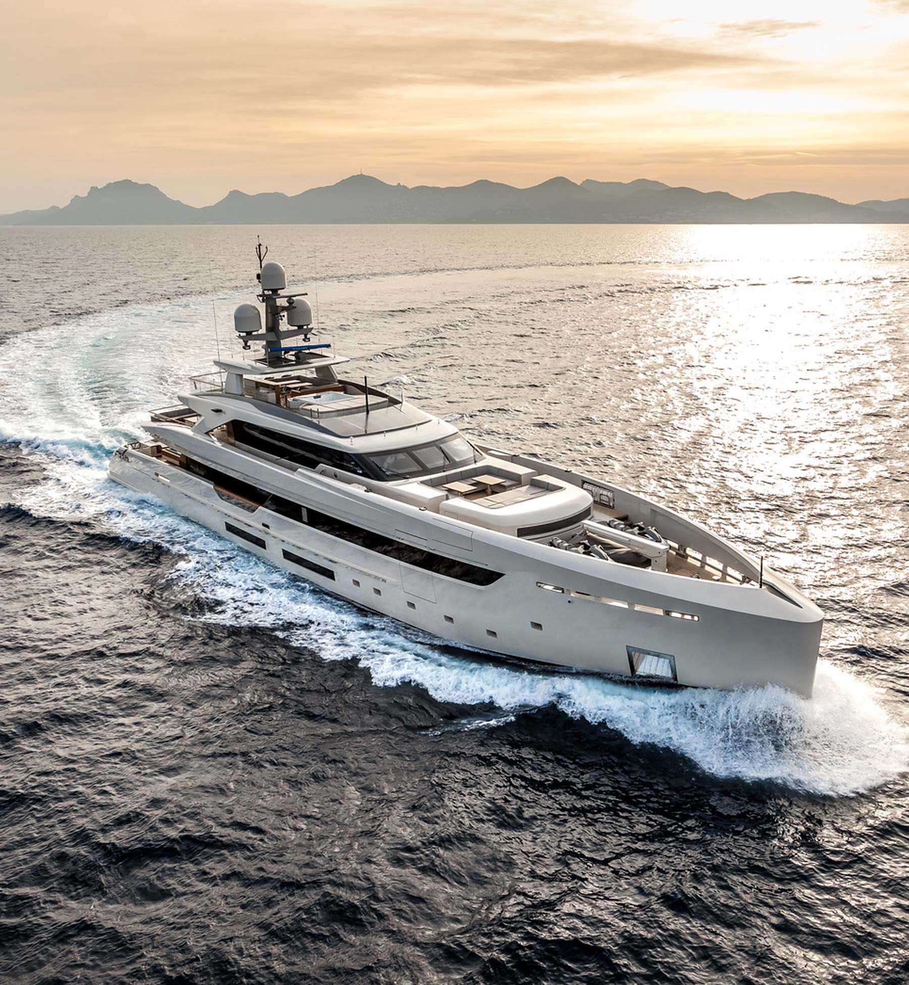 Mega yacht cruising through ocean at sunset