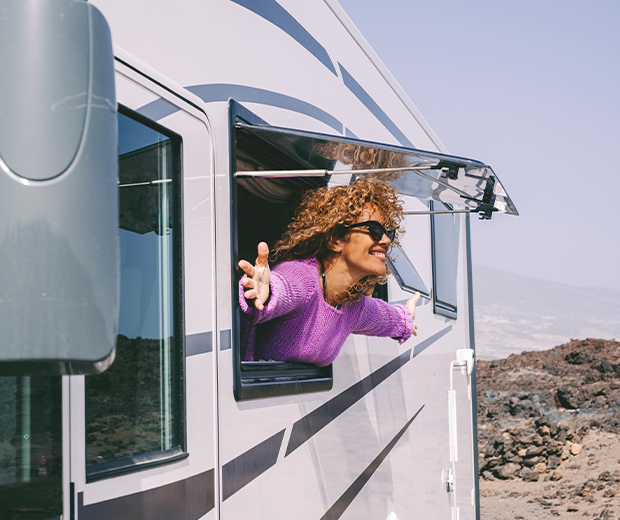Woman looking out rv window with arms out