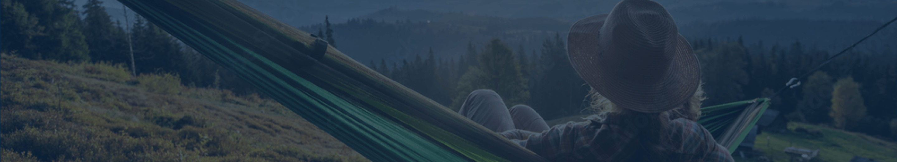 Woman sitting on hammock overlooking mountain forest