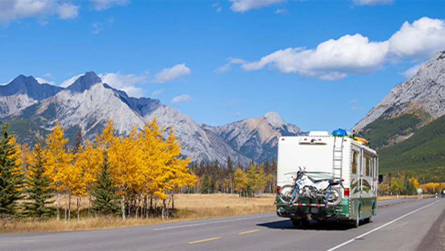 RV on the road with mountain and trees behind