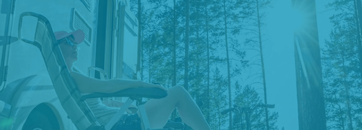 Woman sitting on lounge chair next to RV in the woods