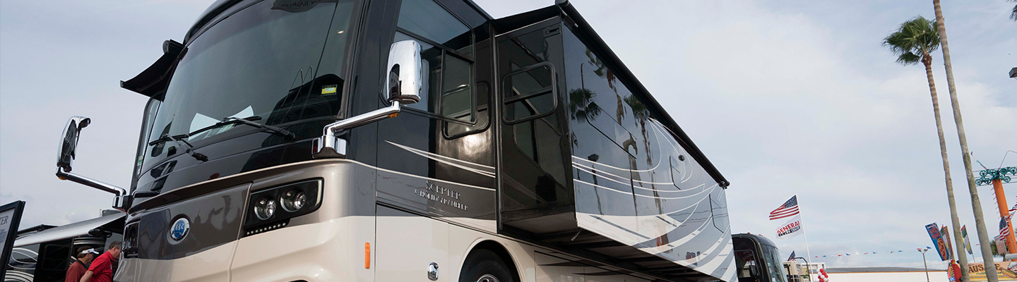 Luxurious, modern RV parked outdoors during the day, showcasing sleek silver and black design.