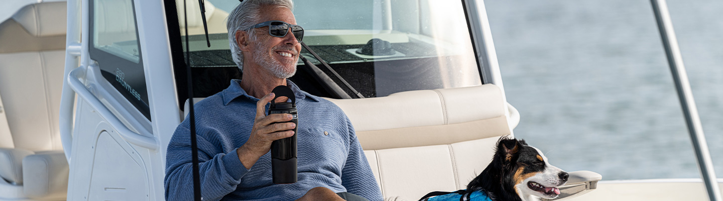 Man and dog sitting on boat smiling