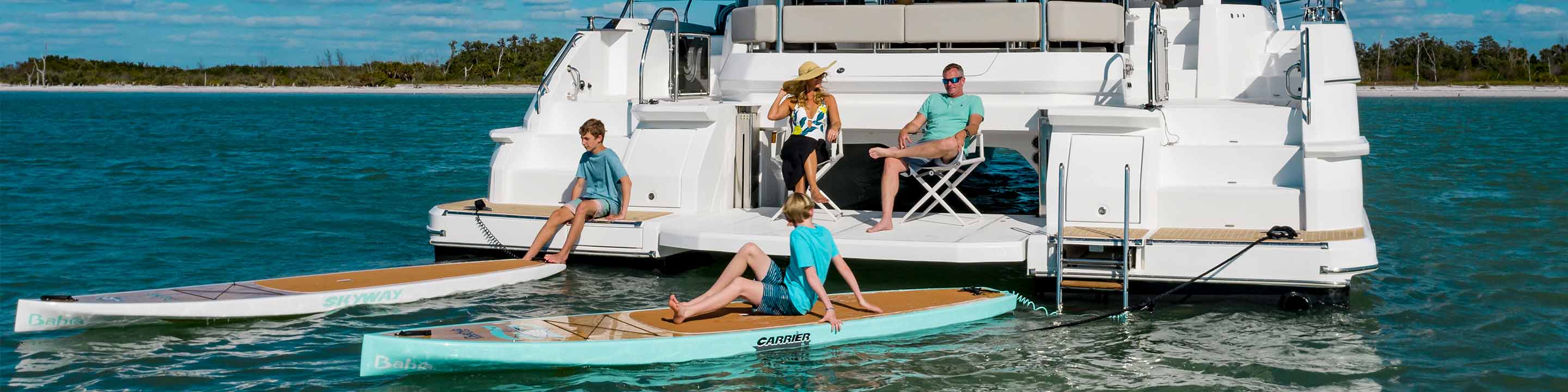 Family with paddle boards sitting on the back of yacht